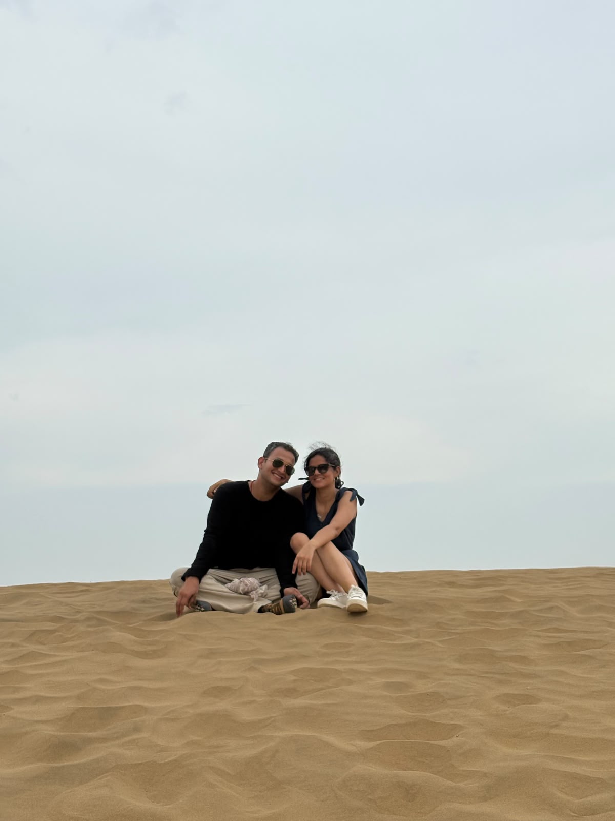 Simran and Varun sitting together on a sand dune